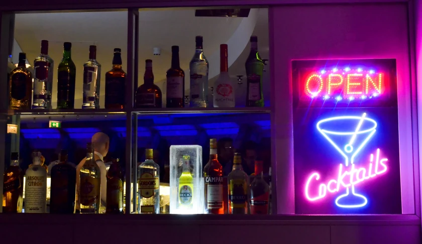 a lighted sign showing open bar bottles