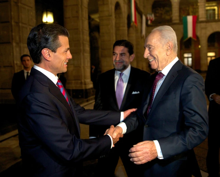 two men shaking hands in front of flags