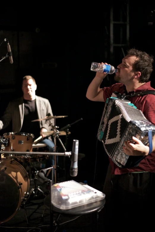 the two men are holding an accordion and a bottle