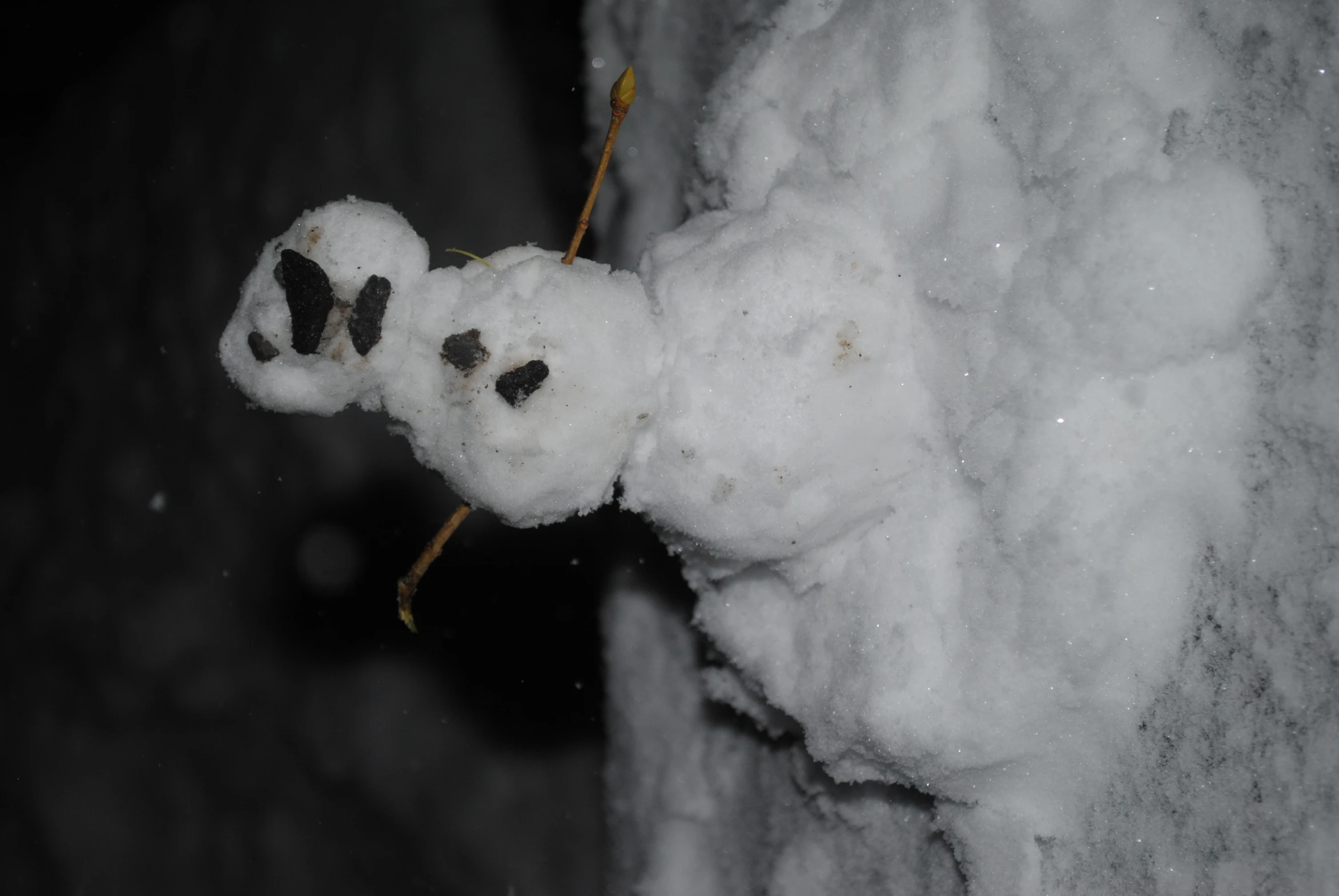 a snowman making a snow man on the edge of the sidewalk
