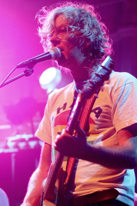 a man holding a guitar singing into a microphone