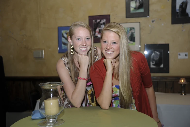 two girls sitting at the table with a light and a bottle of milk