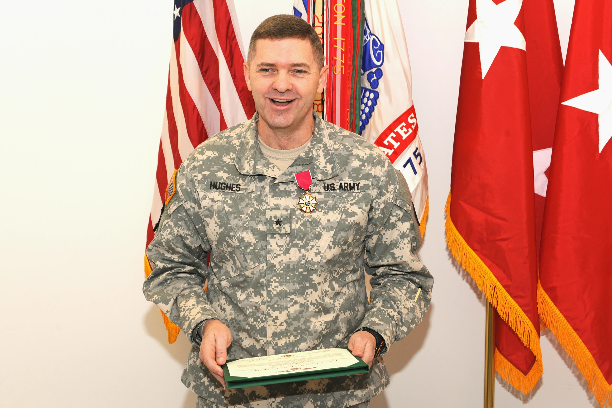 a military man holding a tray while standing in front of american flags