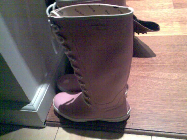 a pair of pink boots are propped against a white door