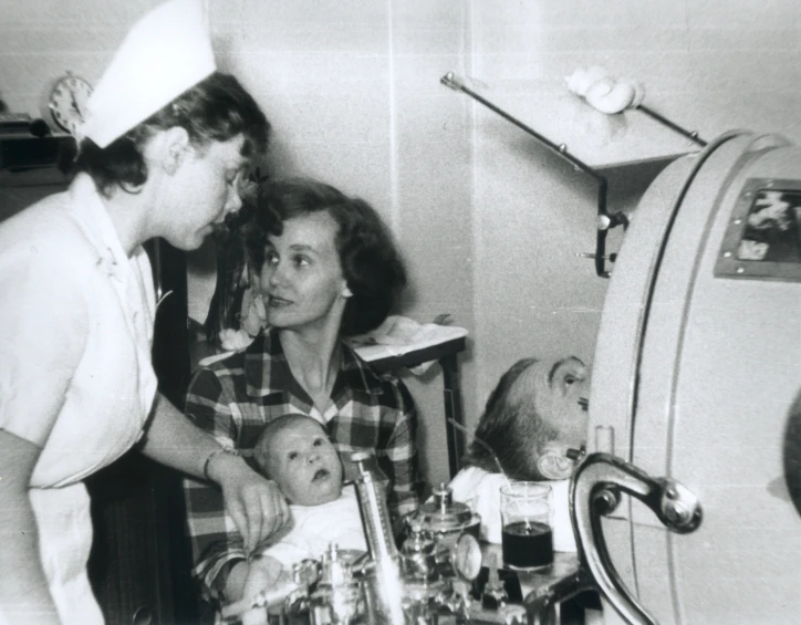 a woman in uniform stands next to a woman holding a baby