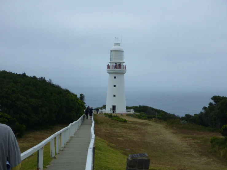 people are walking down the path to a light house