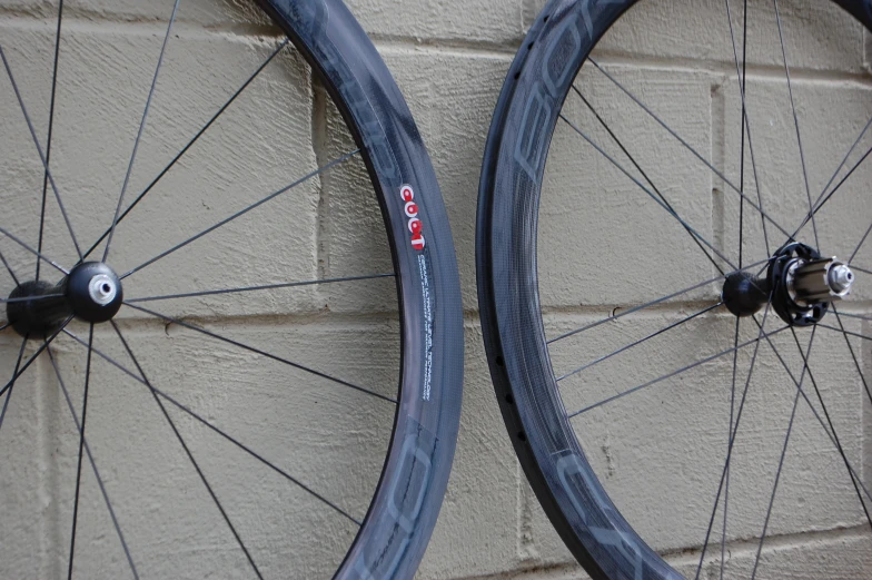 two bicycle wheels side by side against a stone wall