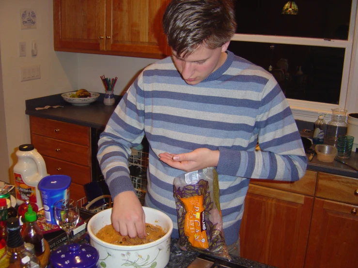 a young man mixing food into a large bowl