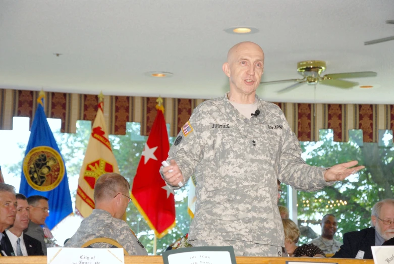an older man in military uniform giving a speech at a podium