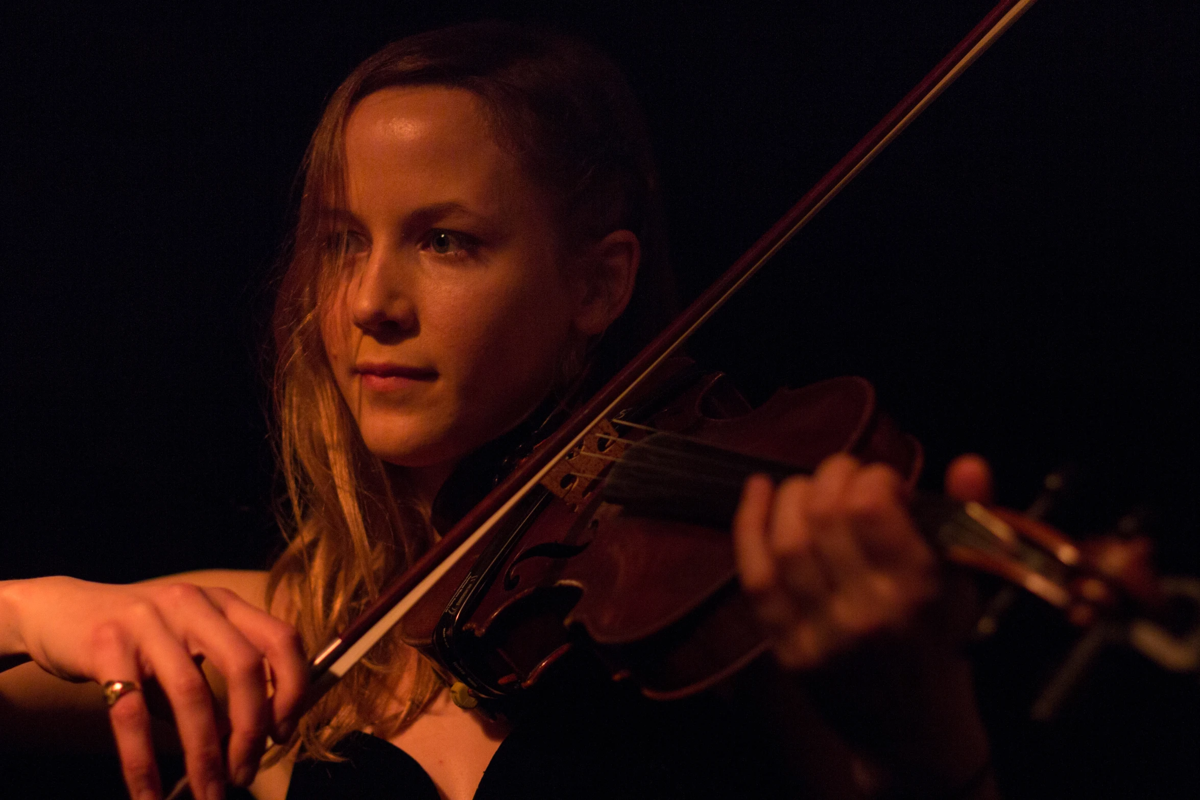 woman holding a violin in the dark with her left arm