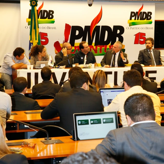 a group of people sitting at tables in front of microphones