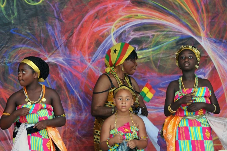 the group of women and children are standing in front of a colorful background