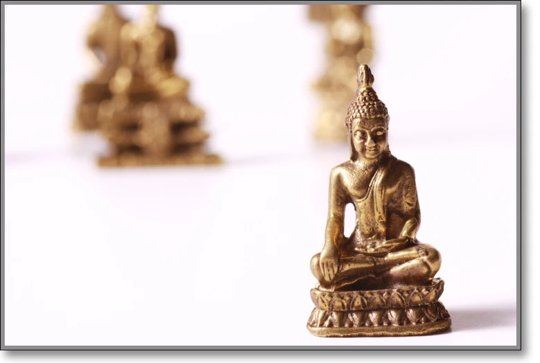small golden buddha statues are on display on a white table