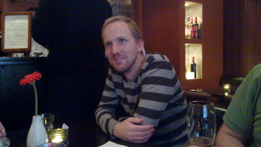 a man sitting at a bar smiling and posing for the camera