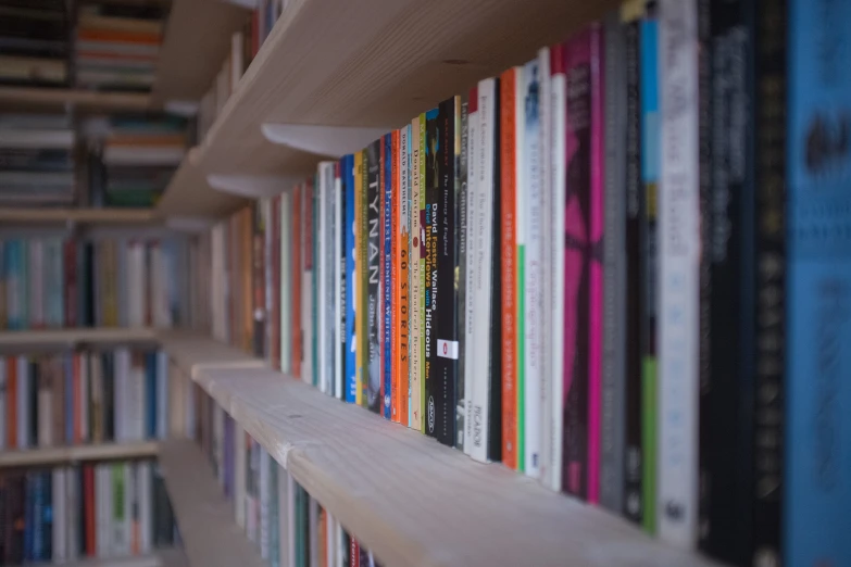 several books are arranged on a wooden shelf