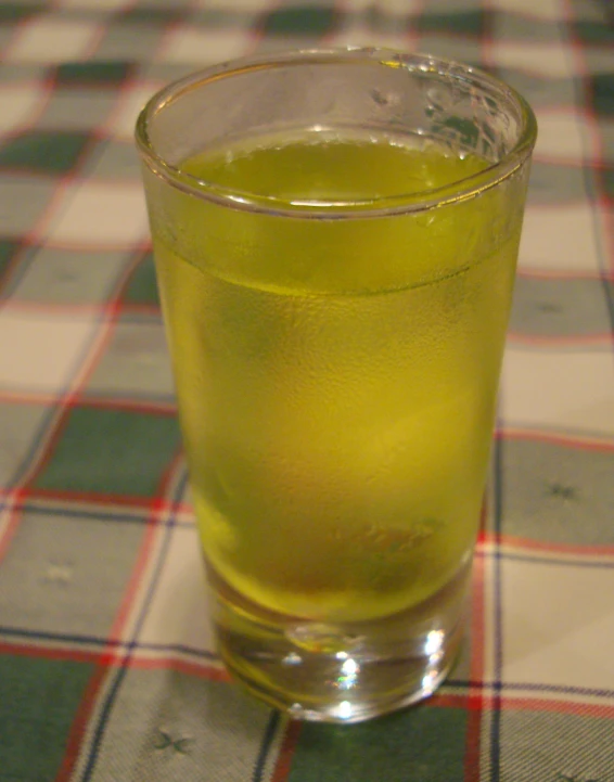 a glass of green liquid sitting on top of a table