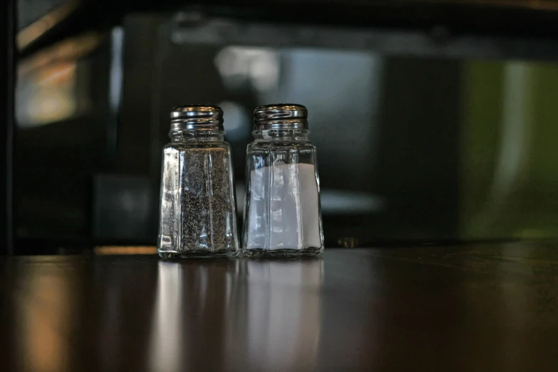 two glass bottles filled with sand on top of a table