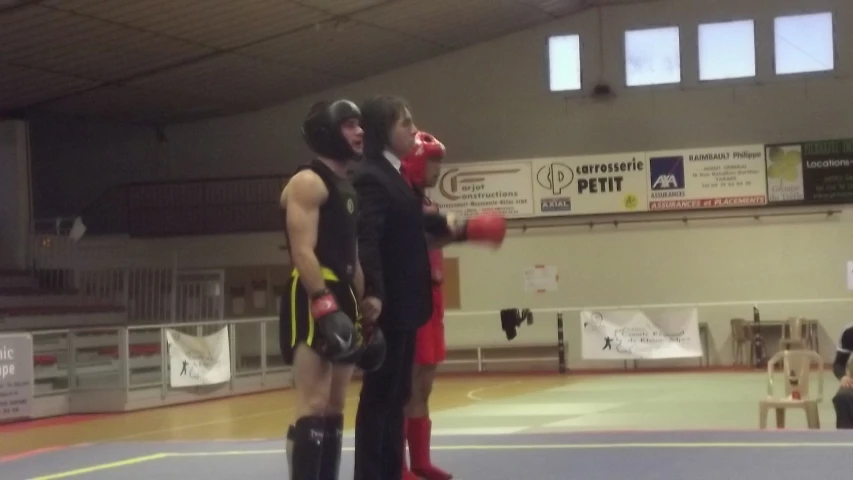 two men in full boxing gear stand on a mat