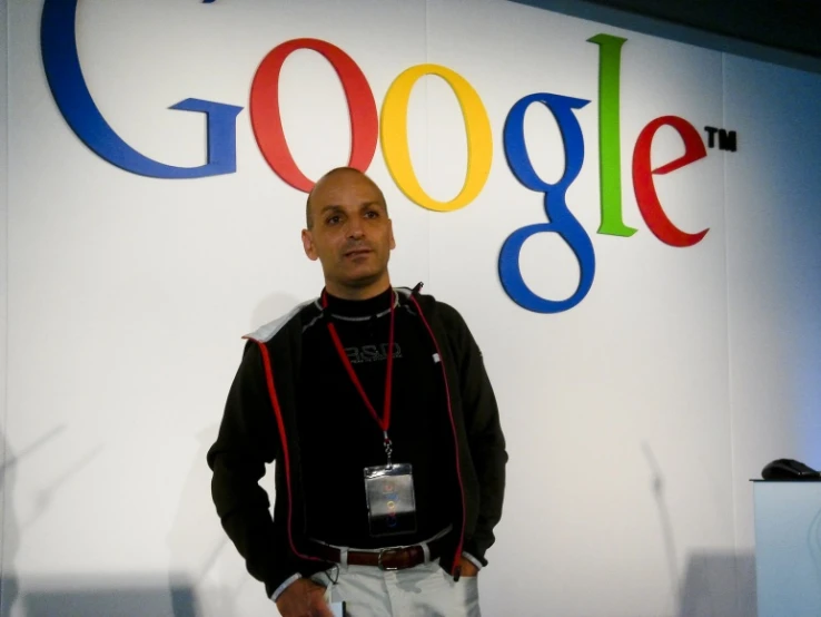 a man standing in front of a sign with the google logo