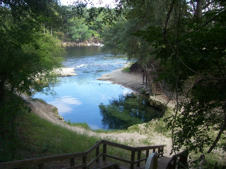 wooden steps lead up to the beach next to a river