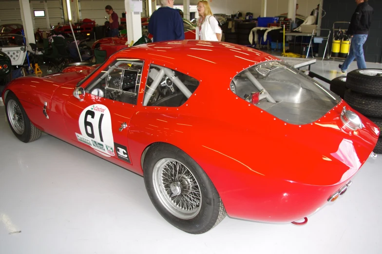 some people standing around a race car that is parked in a garage