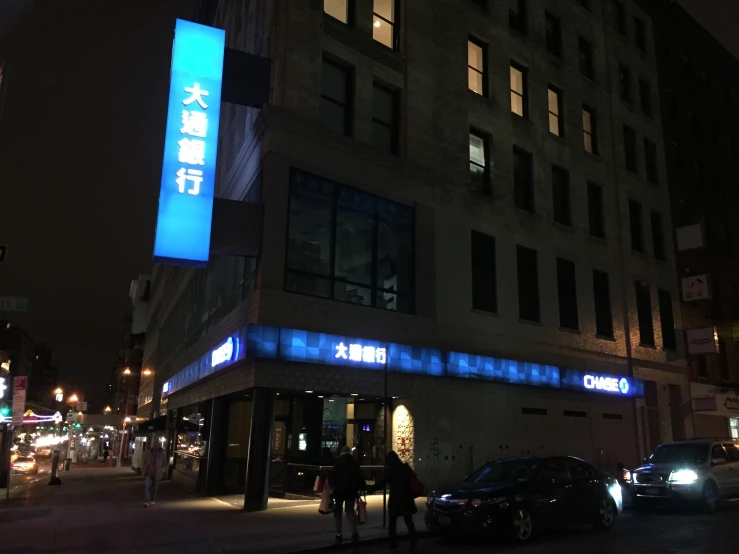 people walking on the sidewalk in front of a building