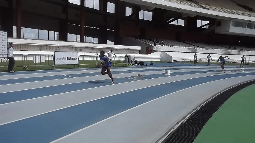 a man running on a blue track near an empty stadium