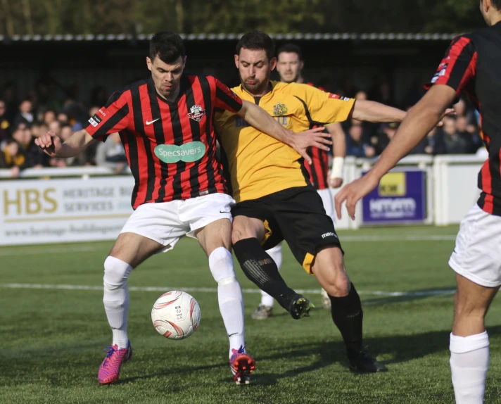 two men in uniforms playing soccer while spectators watch