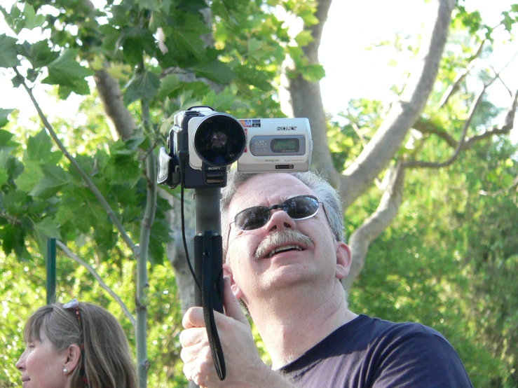 a man holding up a video camera to take a po