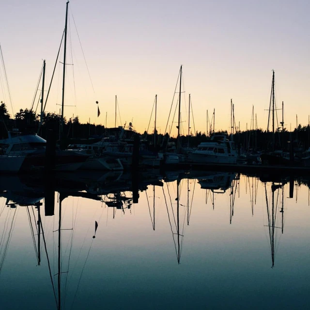 the sun setting on a harbor filled with many boats