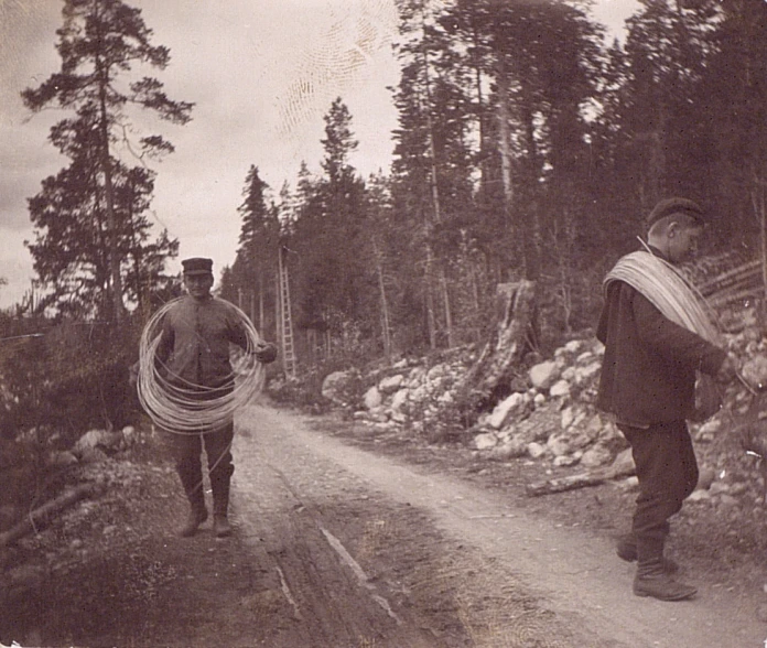 two men carrying large pieces of cloth down a road