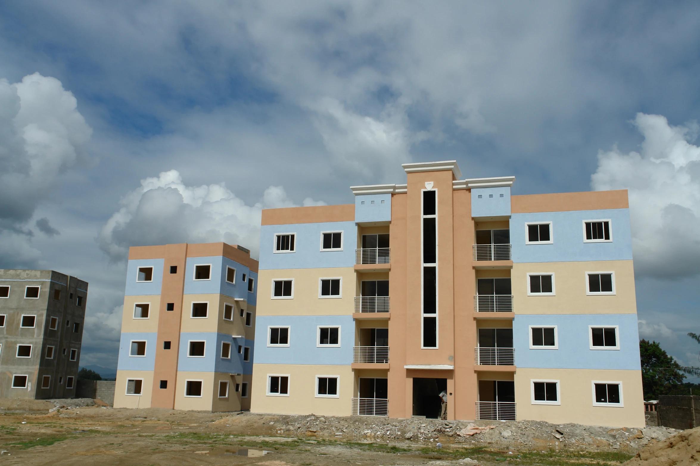 three large apartment buildings in an area with sp trees