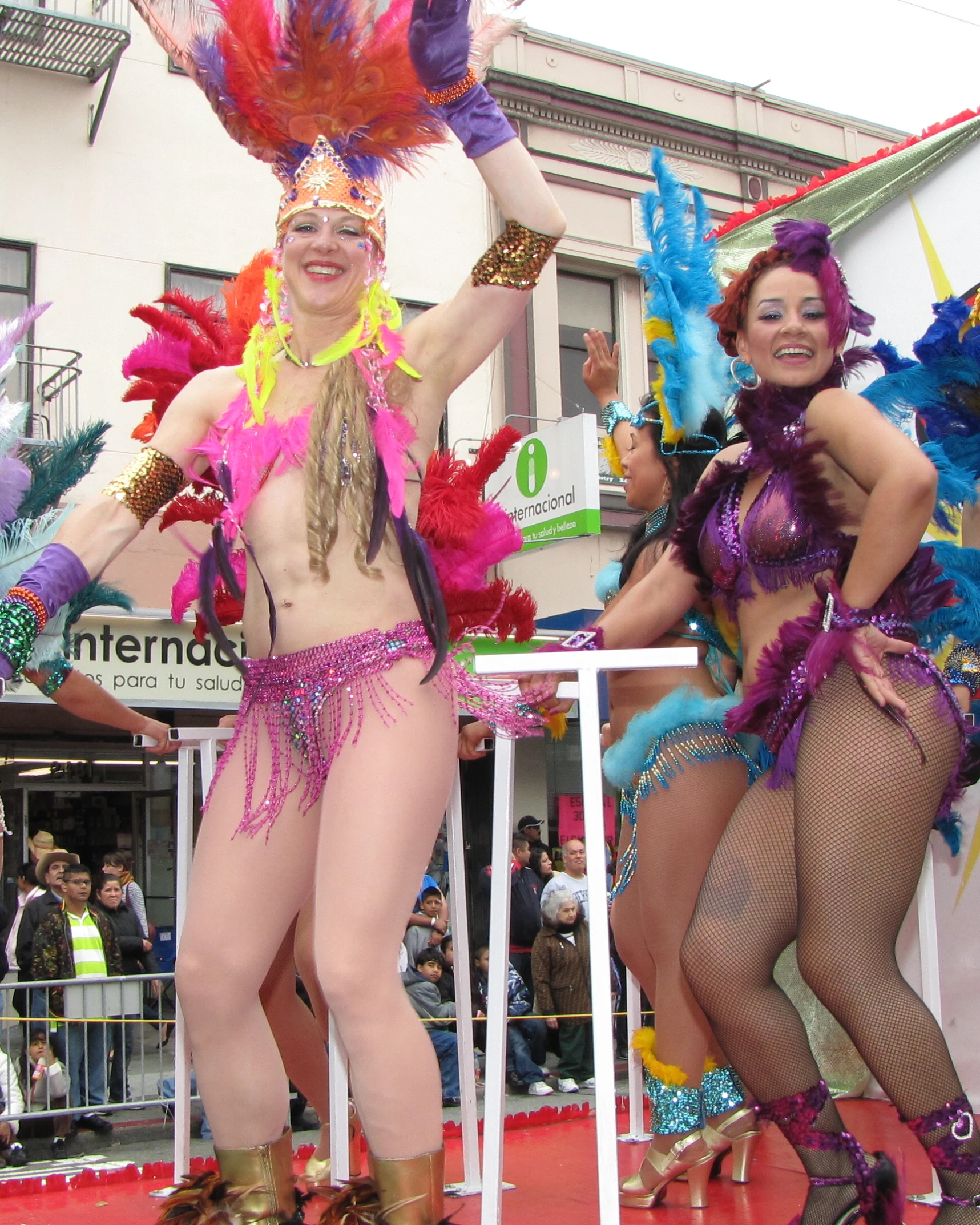 two women in fishnet outfits and one woman with feathers on her head