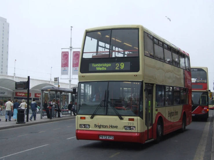 people walking past double decker buses driving down a city street