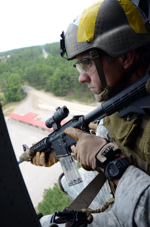 the man has a gun in his hand, while wearing a helmet and uniform