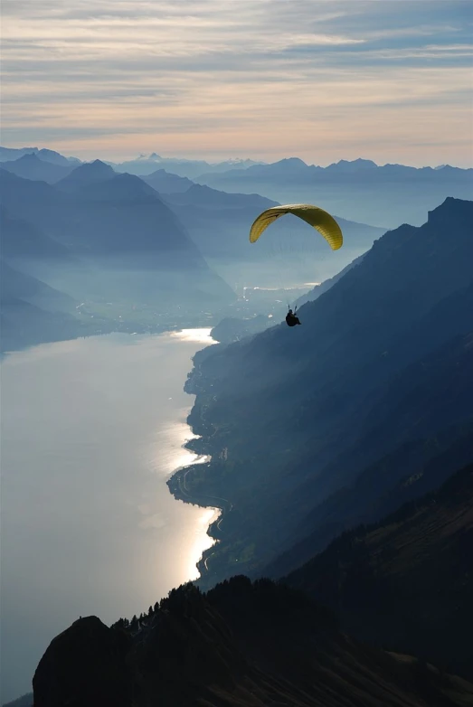 a parachute flying over the mountains in the daytime