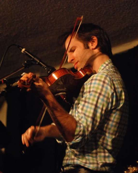 a man playing a violin while standing next to a microphone