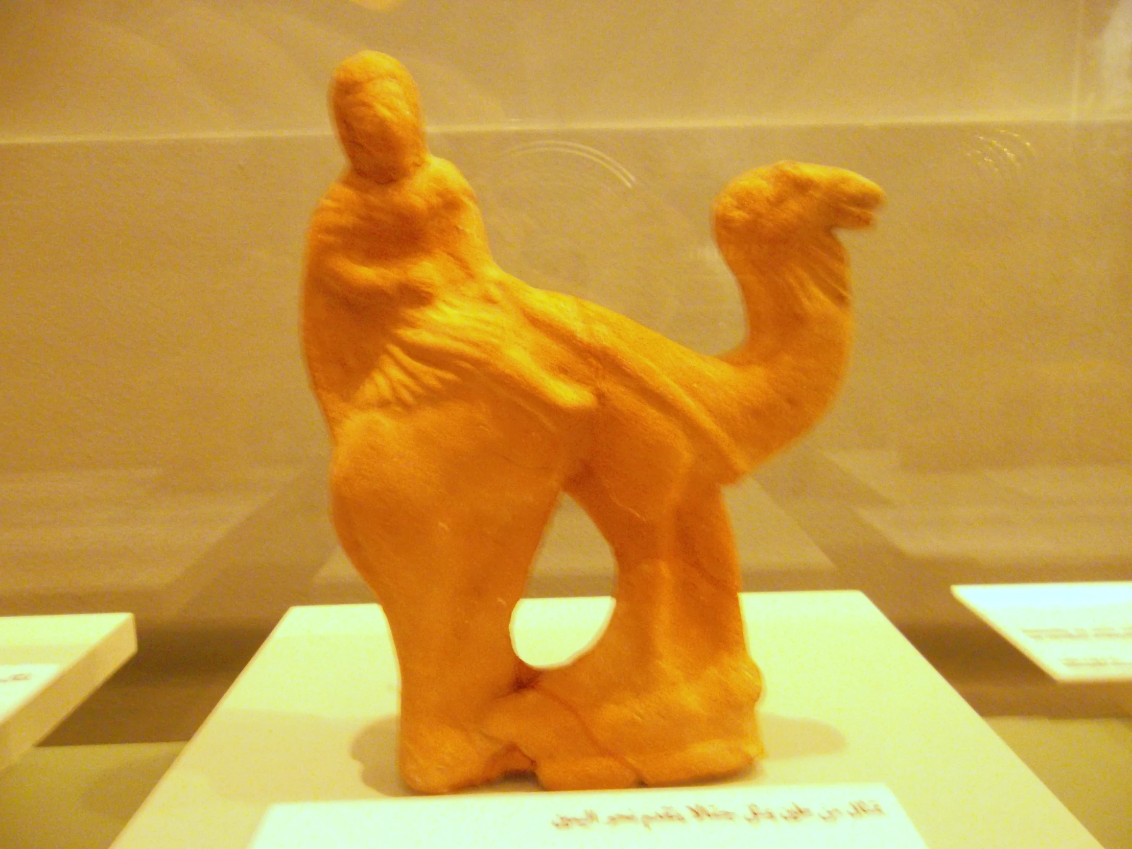 a clay camel on display in a glass case