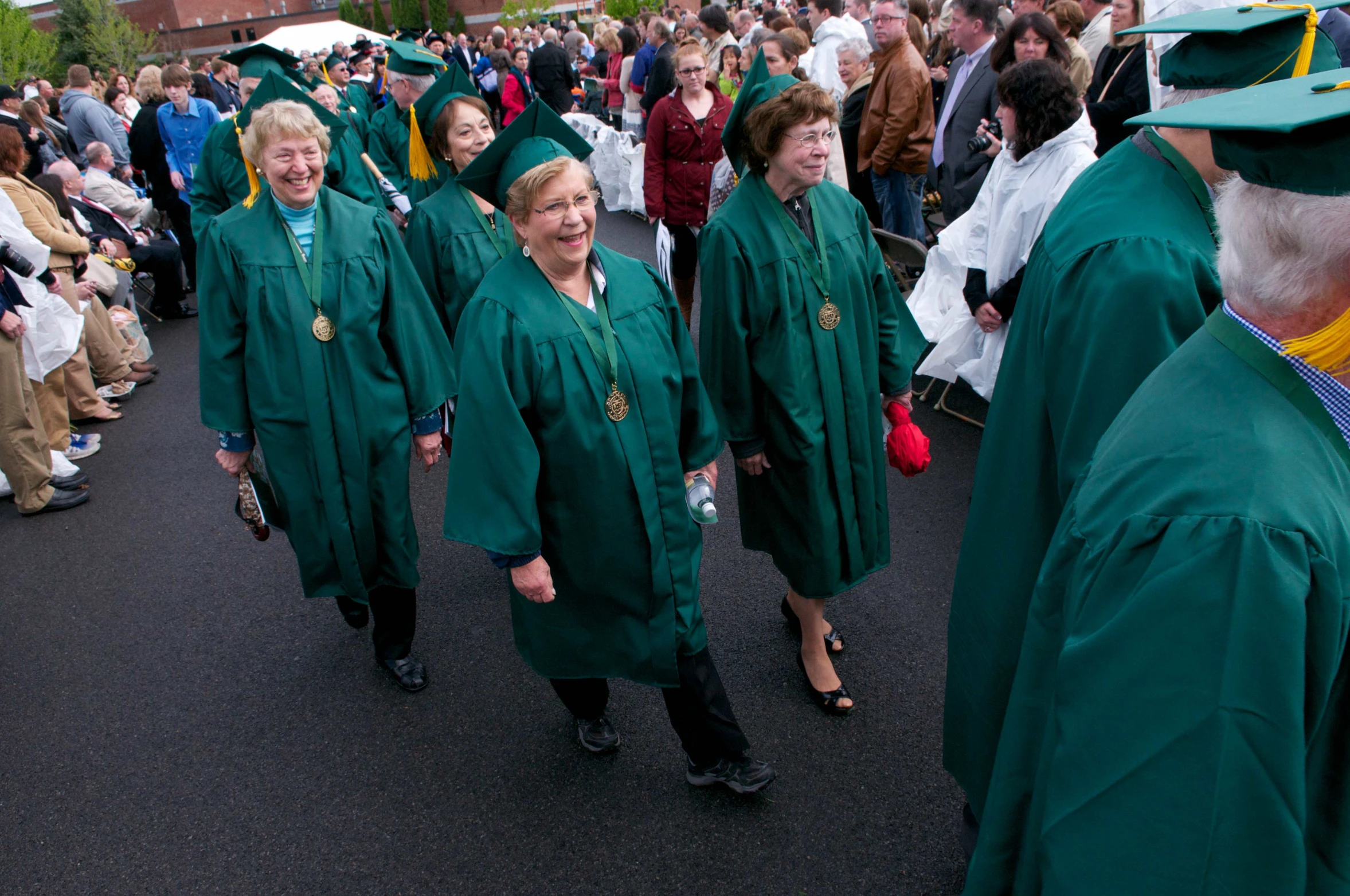 group of smiling graduates walk towards the cameras