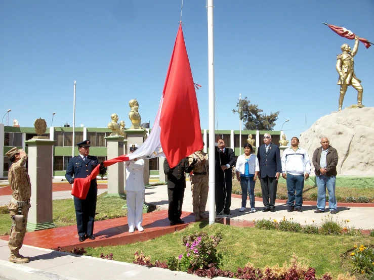 men and women stand around flags at a memorial