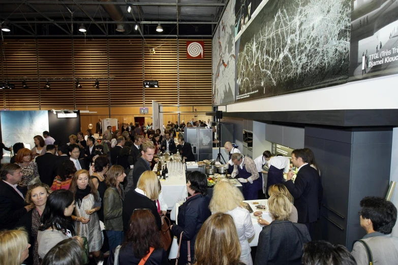 people standing in line and eating food at an indoor event