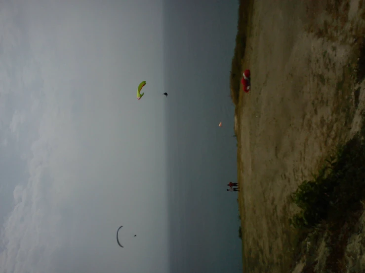 people are flying kites near the ocean and a car