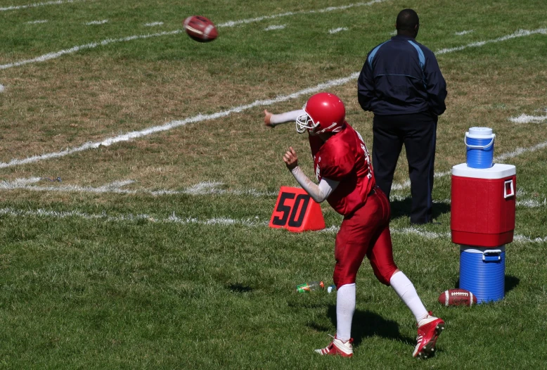 a person in red running a ball while wearing a helmet