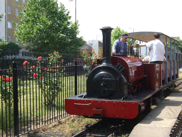 a man in white stands by a small train