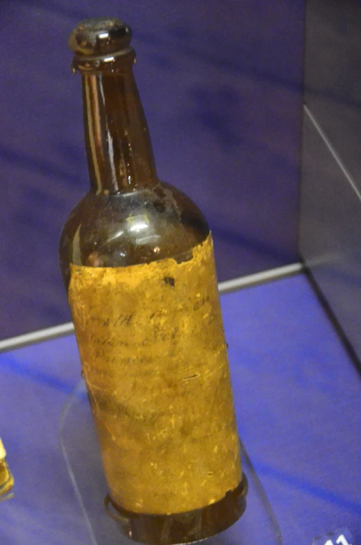 a bottle with an old leather cover is sitting on a glass table