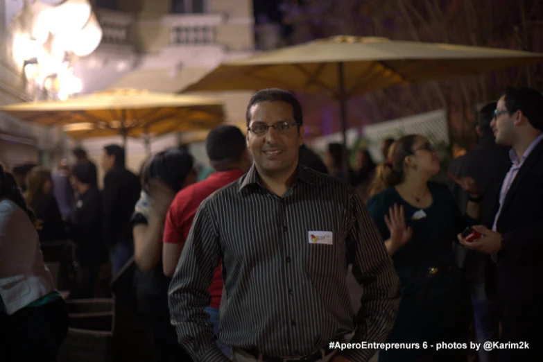 the man has glasses on and is standing in front of a crowd