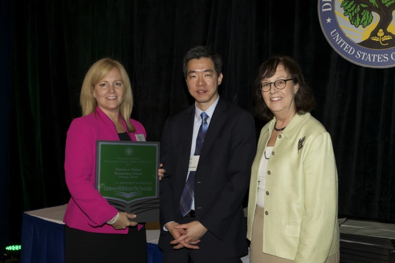 a man and two women standing next to each other holding a plaque