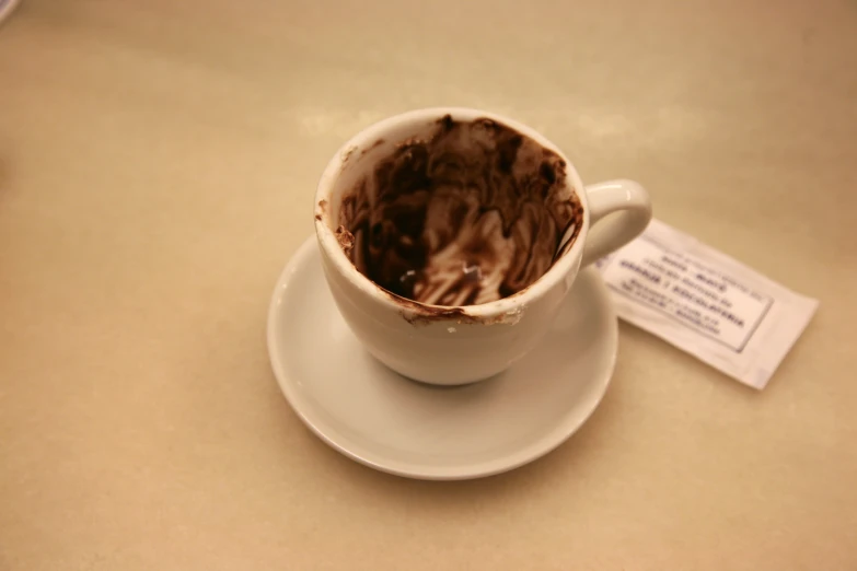 a cup with chocolate inside sits on a saucer