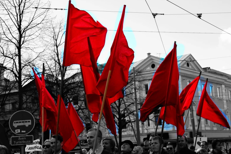 a group of people holding red flags in front of some buildings