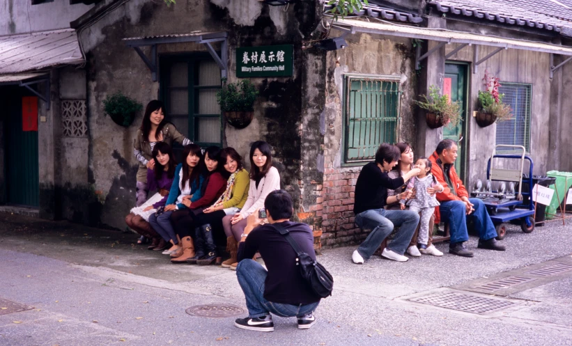 a group of people sit on a curb next to a building